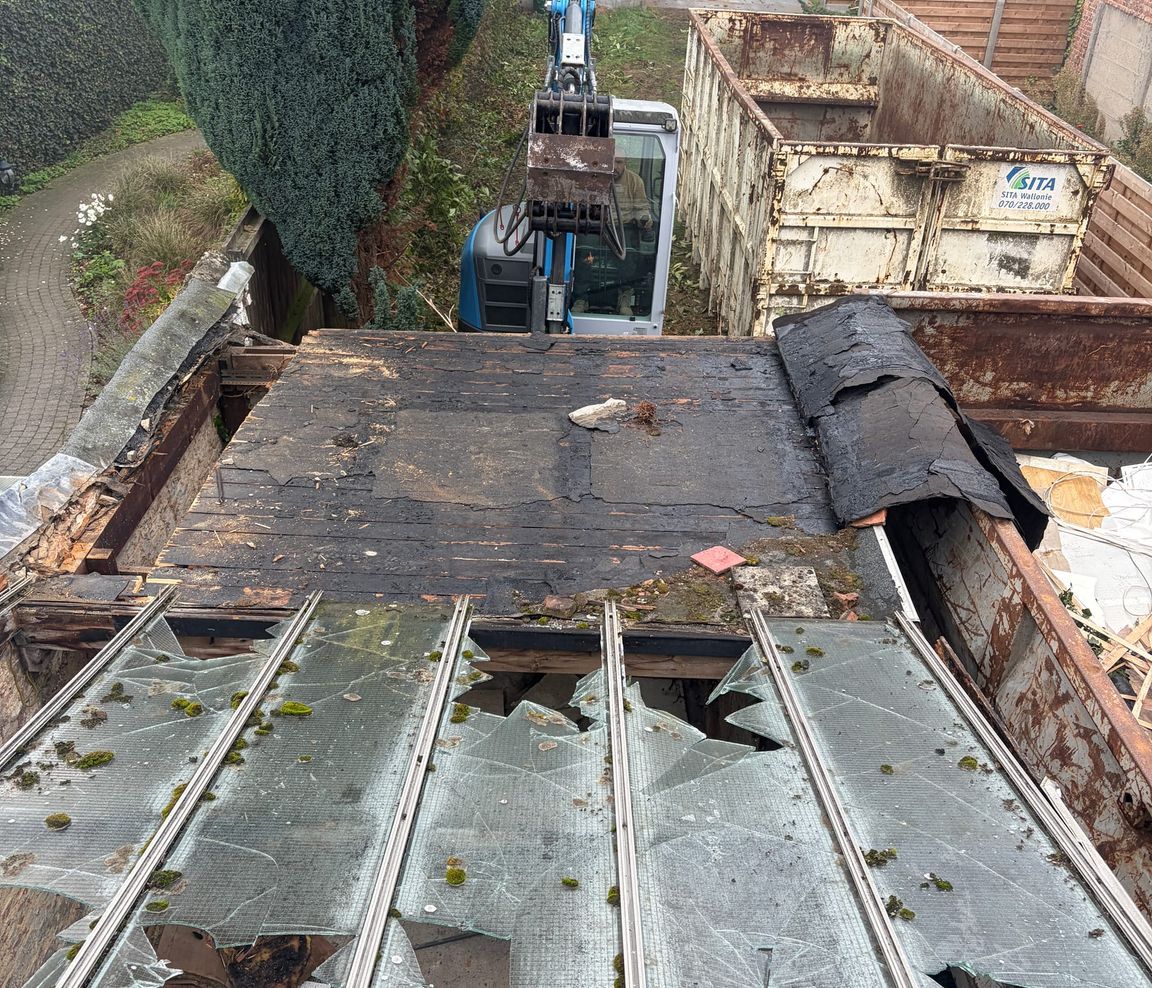 Démolition d’une toiture vue d’en haut, pelleteuse au pied du bâtiment